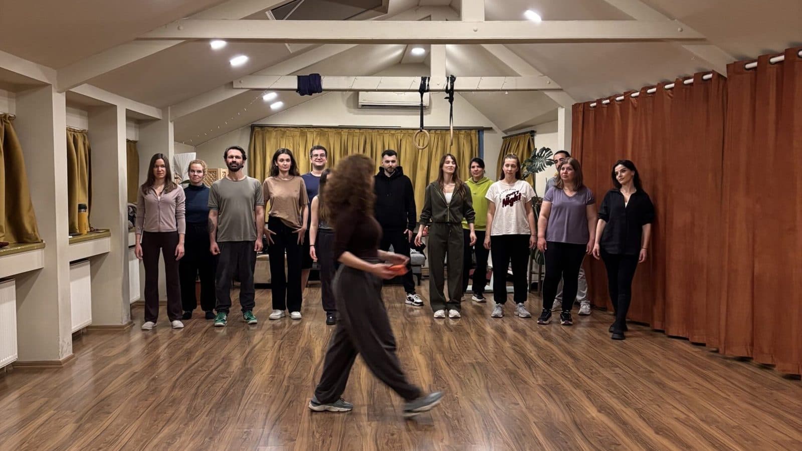 Stüdyoda yarım daire olmuş bir grup, ortada bir katılımcı yürüyor
